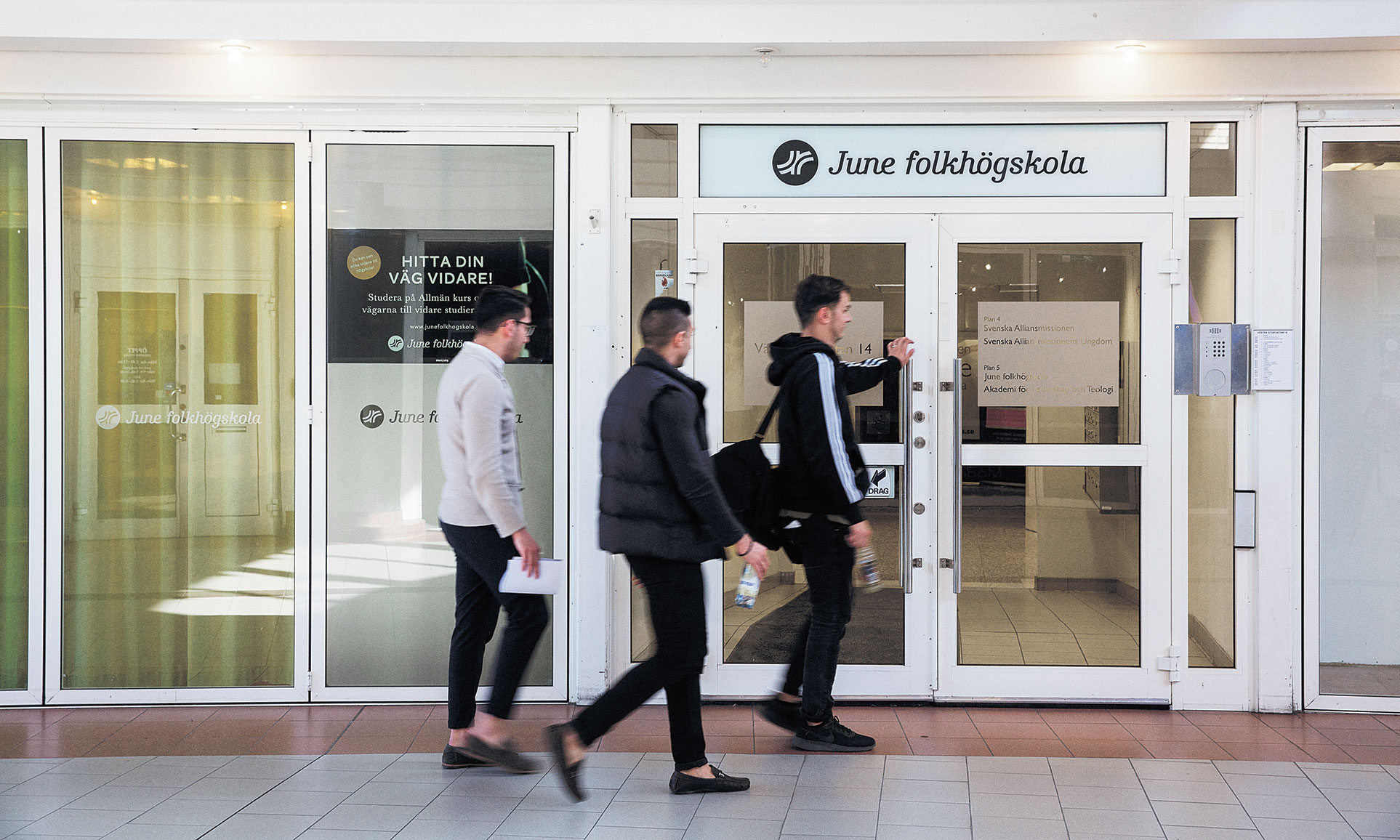 Tre killar är på väg att gå in i June folkhögskolas ytterdörr i Juneporten.