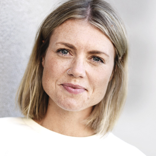 En kvinna med blont hår och ljus tröja.